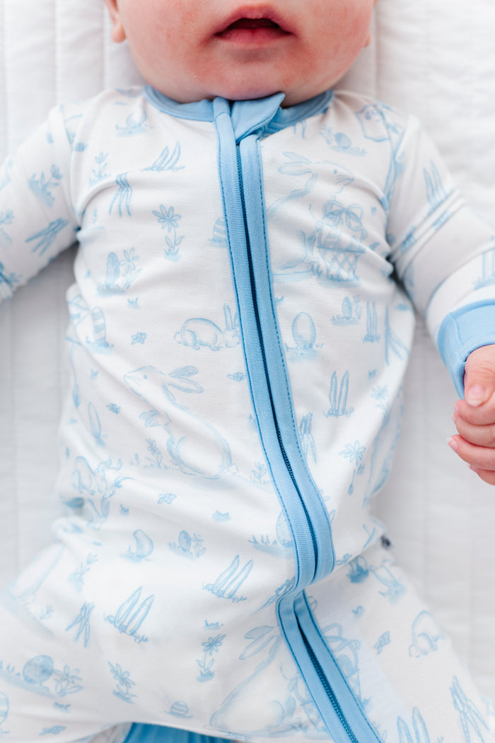 Baby in a blue and white patterned bamboo convertible romper with a zipper