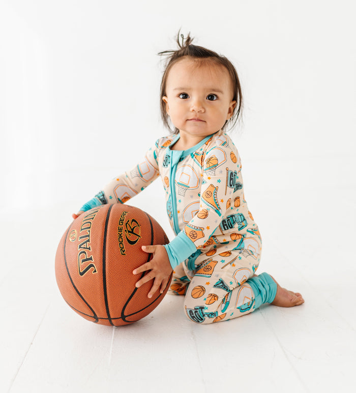 Child wearing a bamboo pajama with basketball design holding a Spalding basketball on a white background