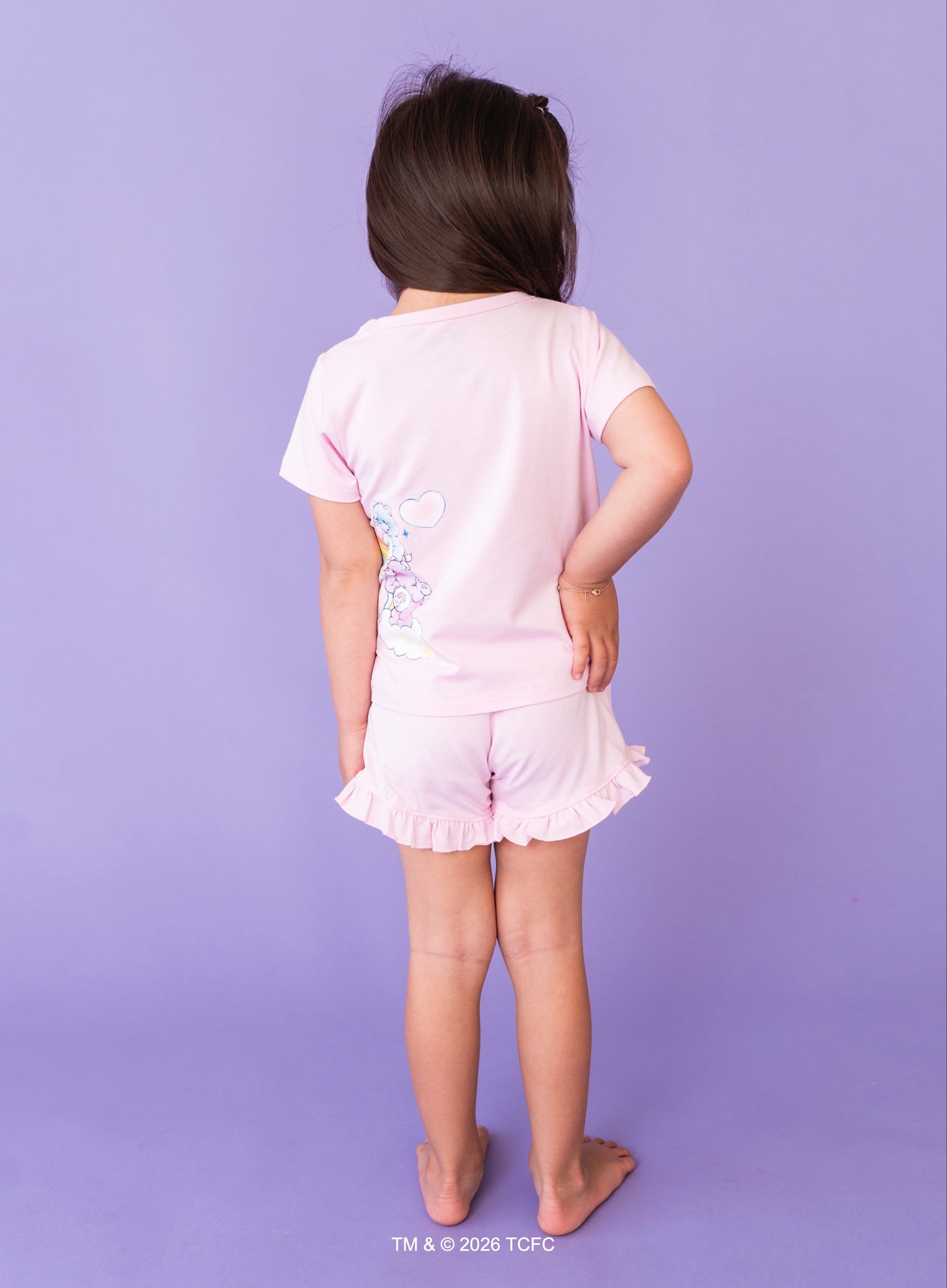 Child wearing a lilac Care Bears™ outfit on a purple background