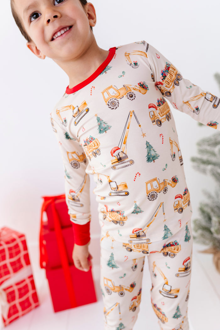 An up-close shot of Merry Machinery pajamas featuring construction trucks moving trees, candy canes, and other festive items.