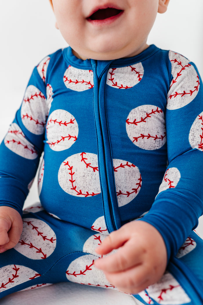 Baby wearing a blue bamboo romper with baseball pattern