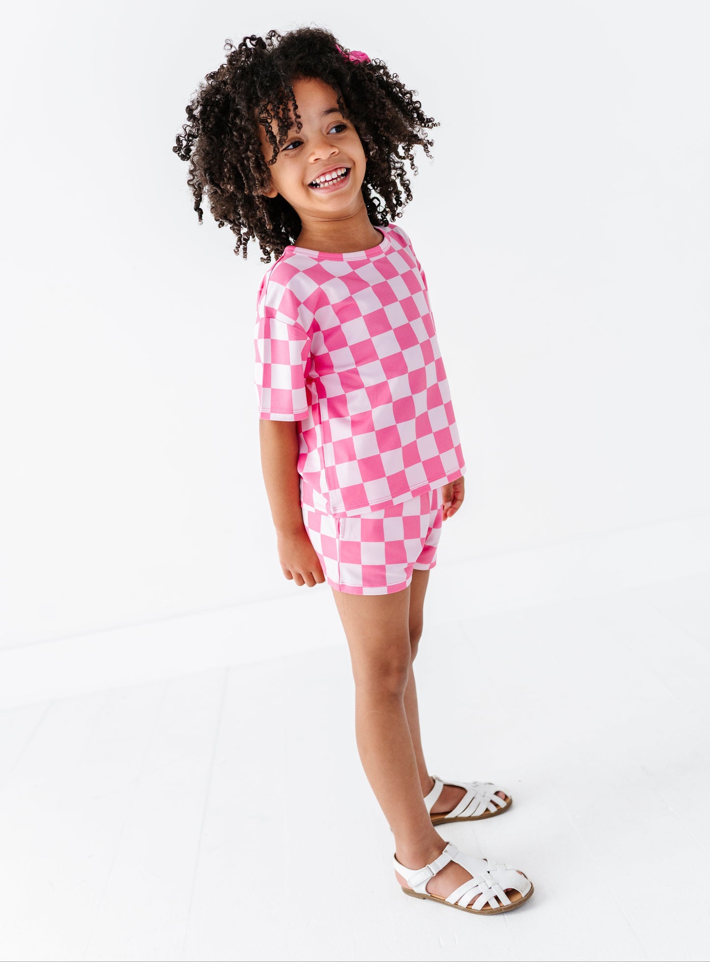 Child wearing a pink checkered outfit on a white background