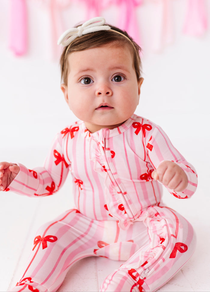 Baby wearing Ruby Ribbons ruffle convertible romper in pink and red stripe bamboo fabric