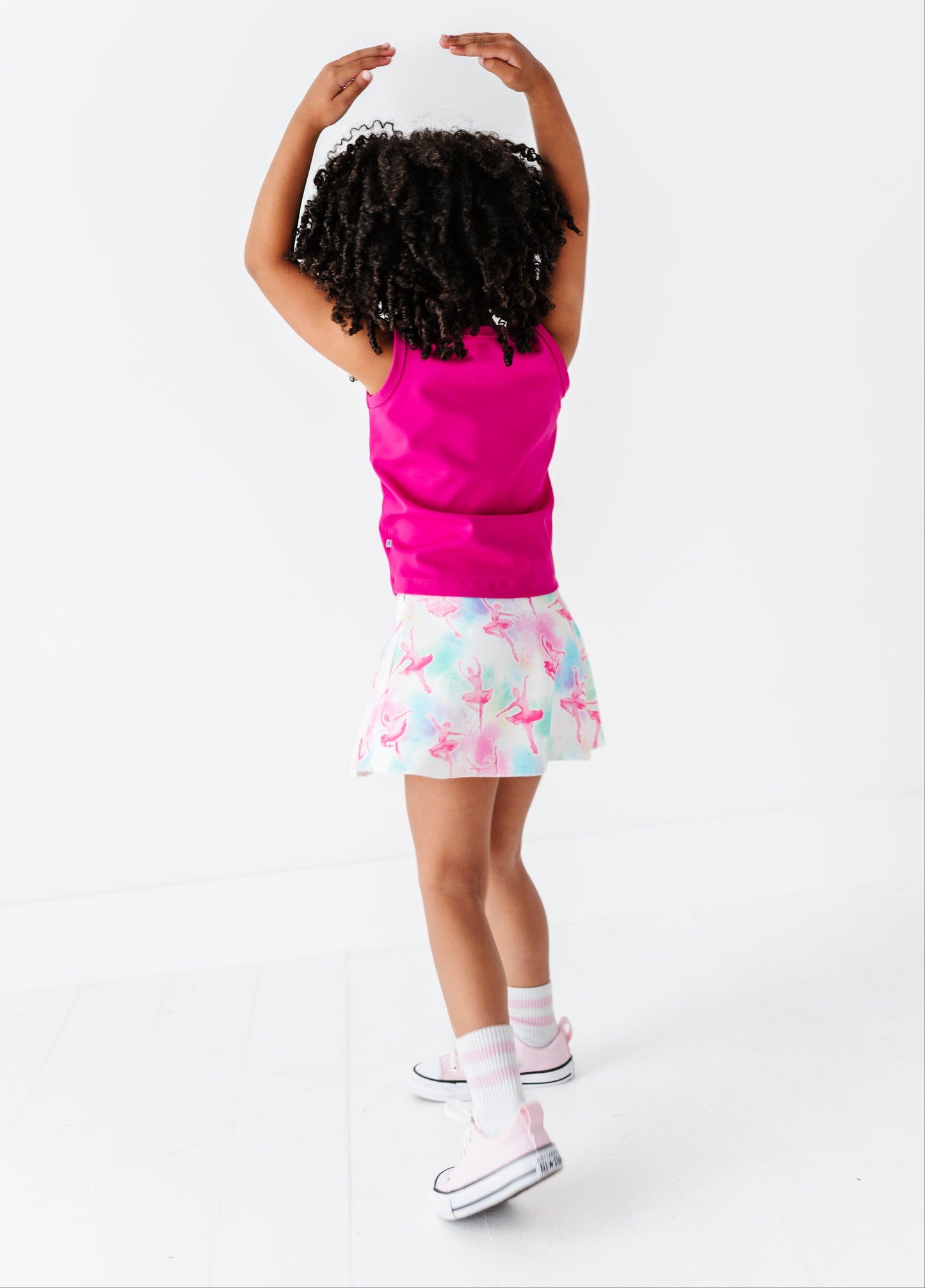 Child wearing a pink top and colorful skirt on a white background