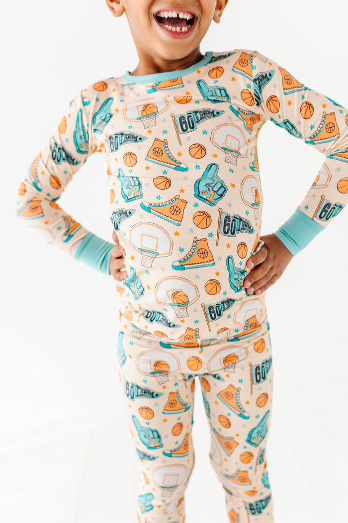 Child wearing a long-sleeve bamboo pajama set with sports-themed design on a white background