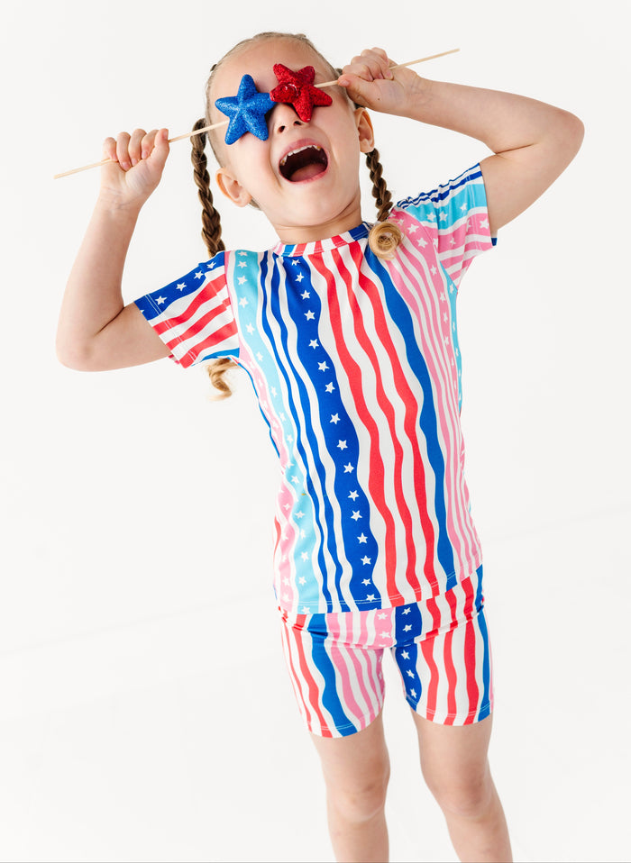 Child wearing a colorful American flag-themed bamboo short set with a white background