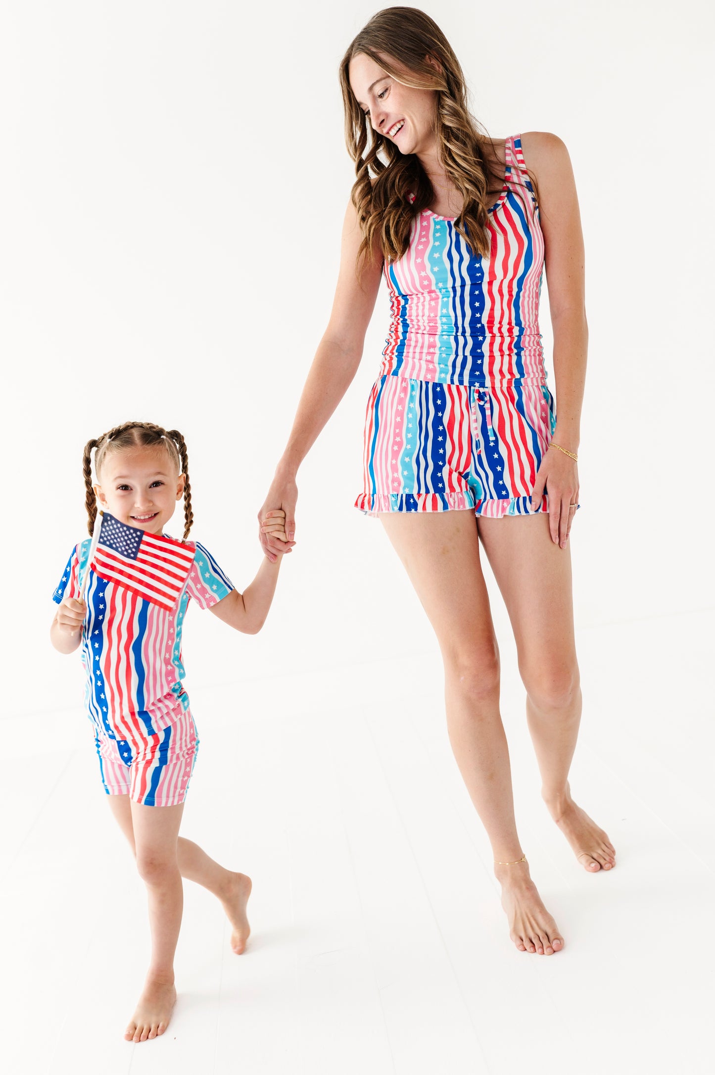 Woman and child wearing matching red, white, and blue bamboo pajama sets on a white background