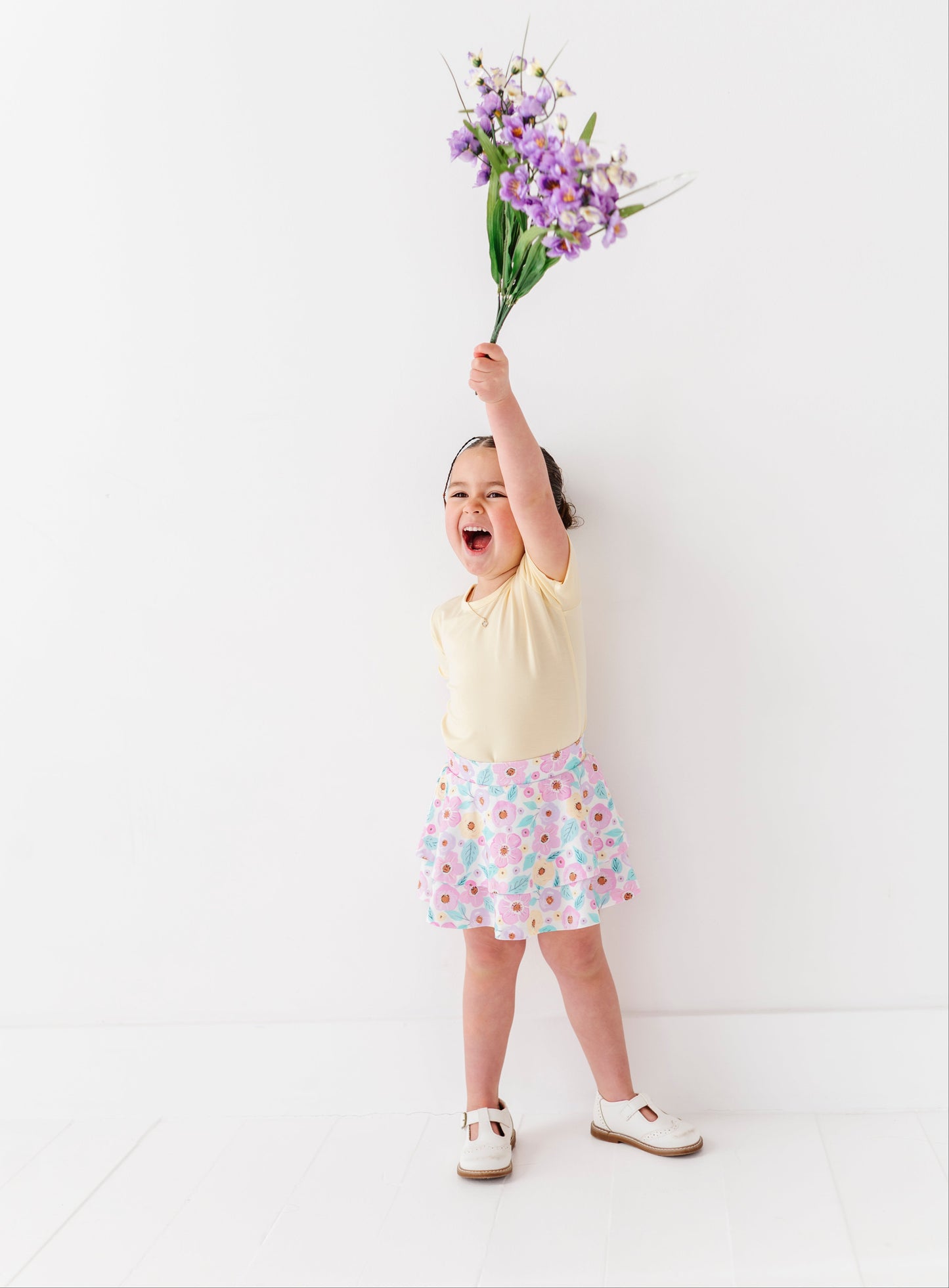 Child holding a bouquet of purple flowers against a white background