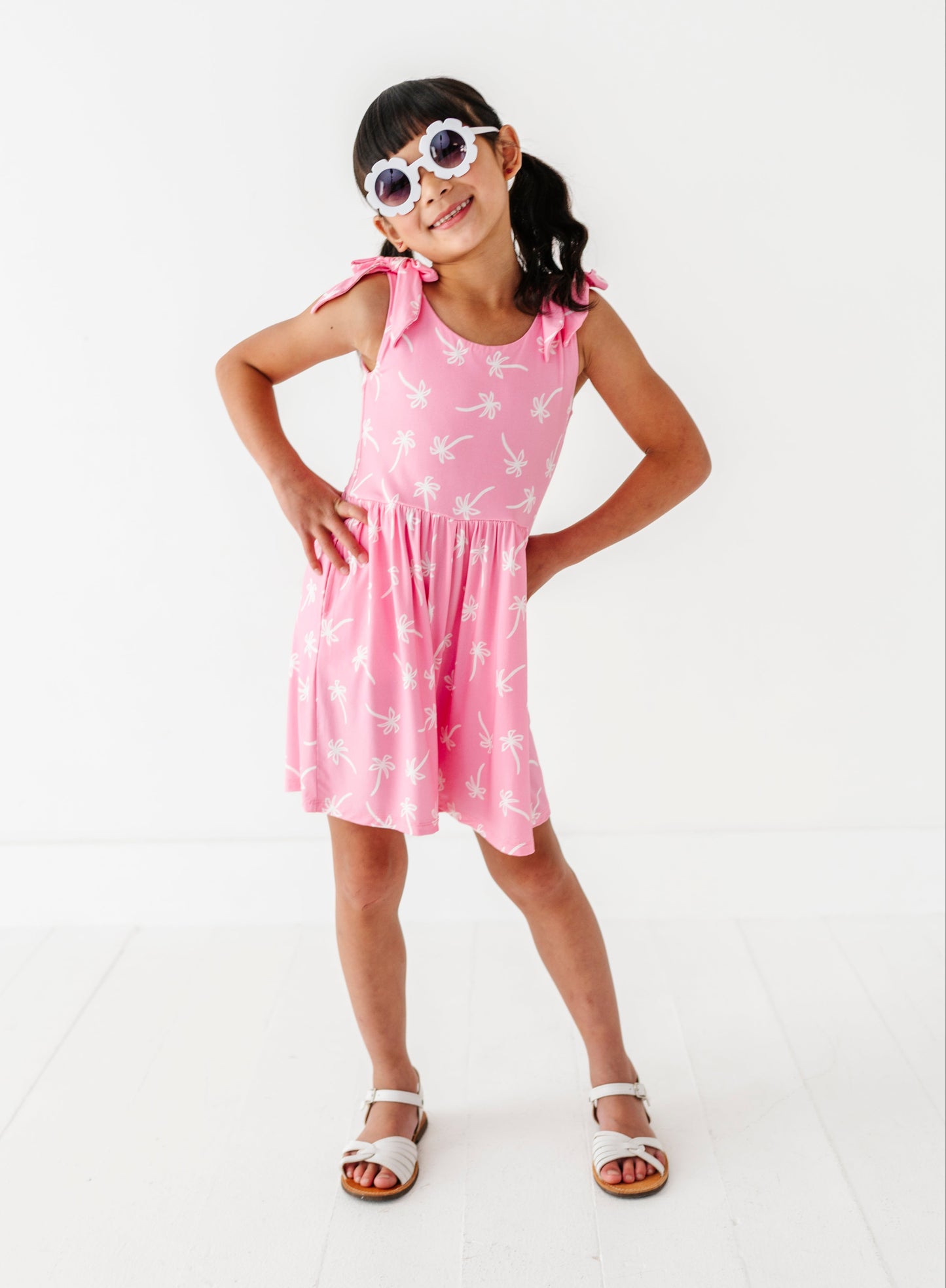 Young girl wearing a pink dress with white patterns on a white background