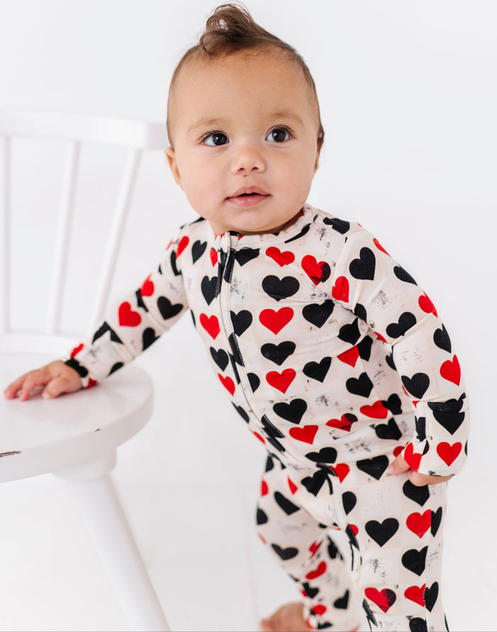 Baby wearing King of Hearts convertible bamboo romper with red and black heart print