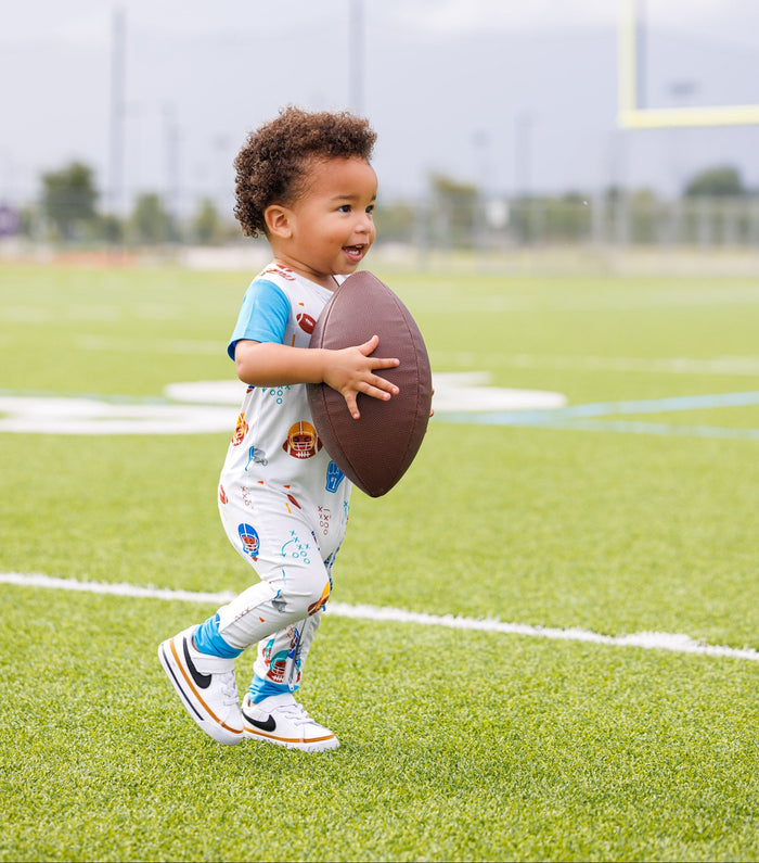 Child holding a football on a sports field
