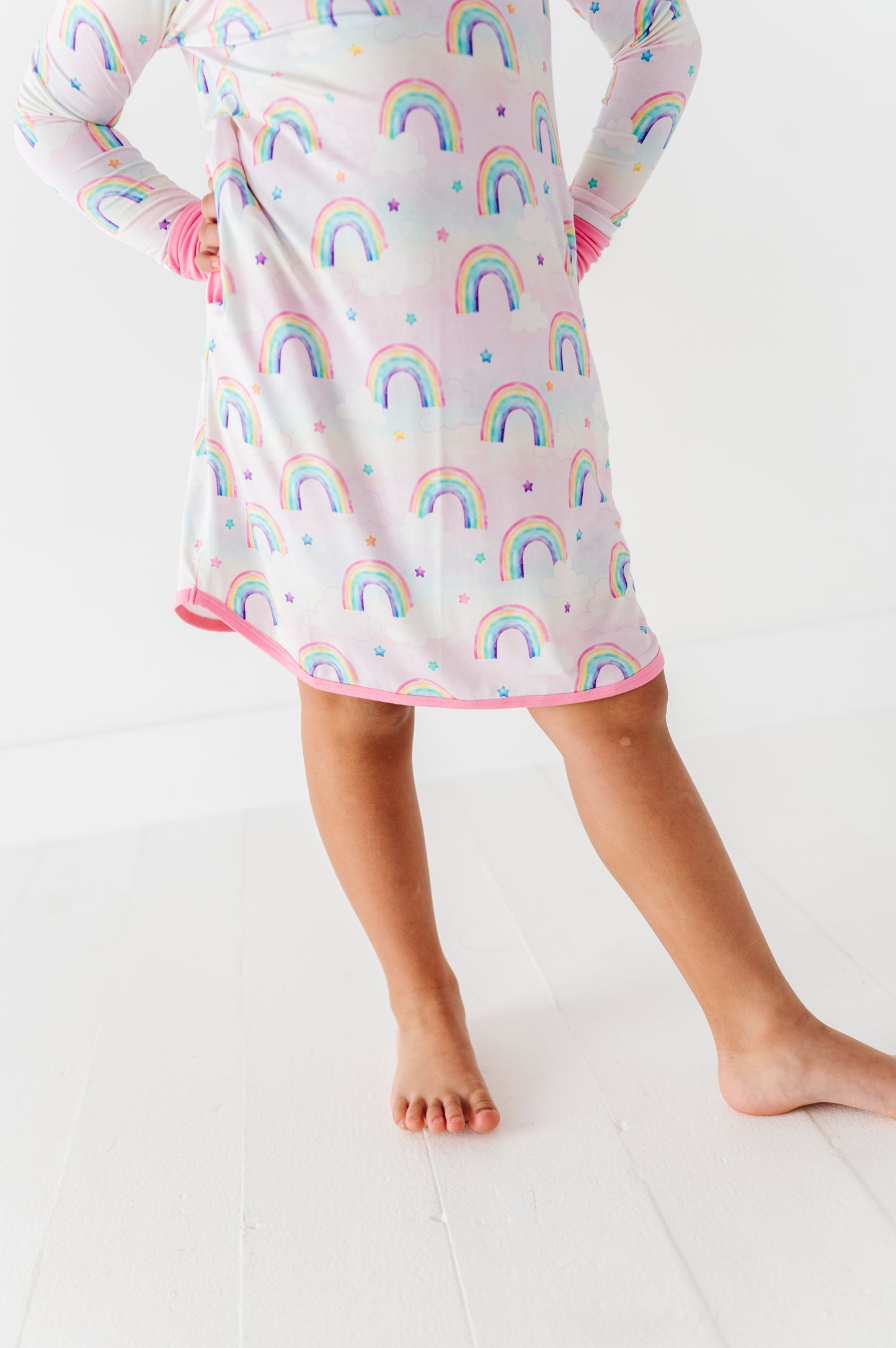 Child wearing a nightgown with watercolor rainbow pattern on a white background