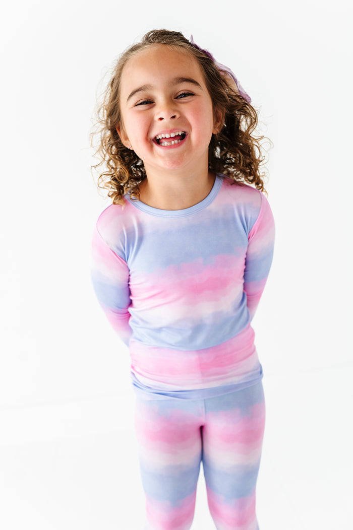 Child wearing a pastel tie-dye bamboo pajama set on a white background