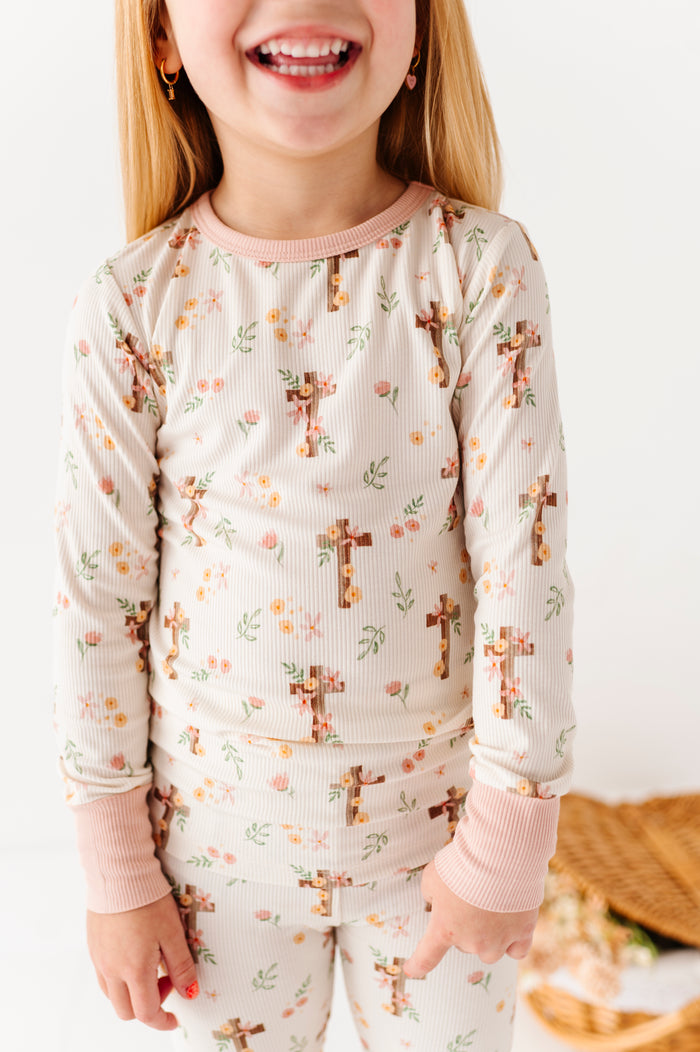 Child wearing an Easter bamboo pajama set with cross pattern on a white background