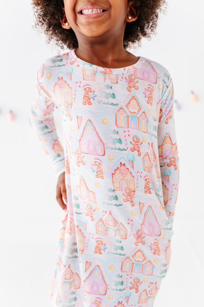 A close-up detail shot of a Christmas gingerbread-themed bamboo nightgown on a little girl standing in a bright white room