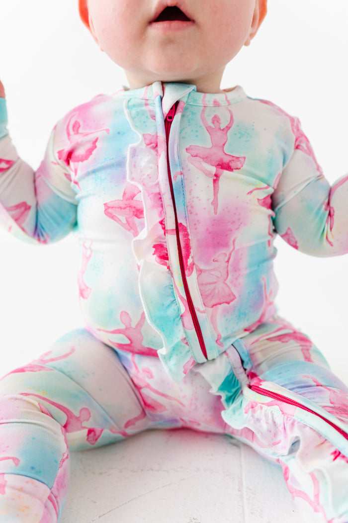 Baby in a watercolor bamboo convertible romper against a white background