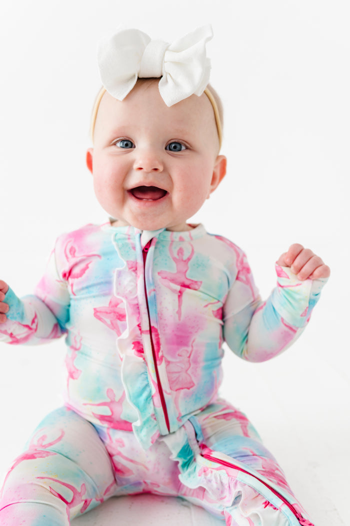 Baby wearing a bamboo zip romper featuring watercolor ballerinas on a white background