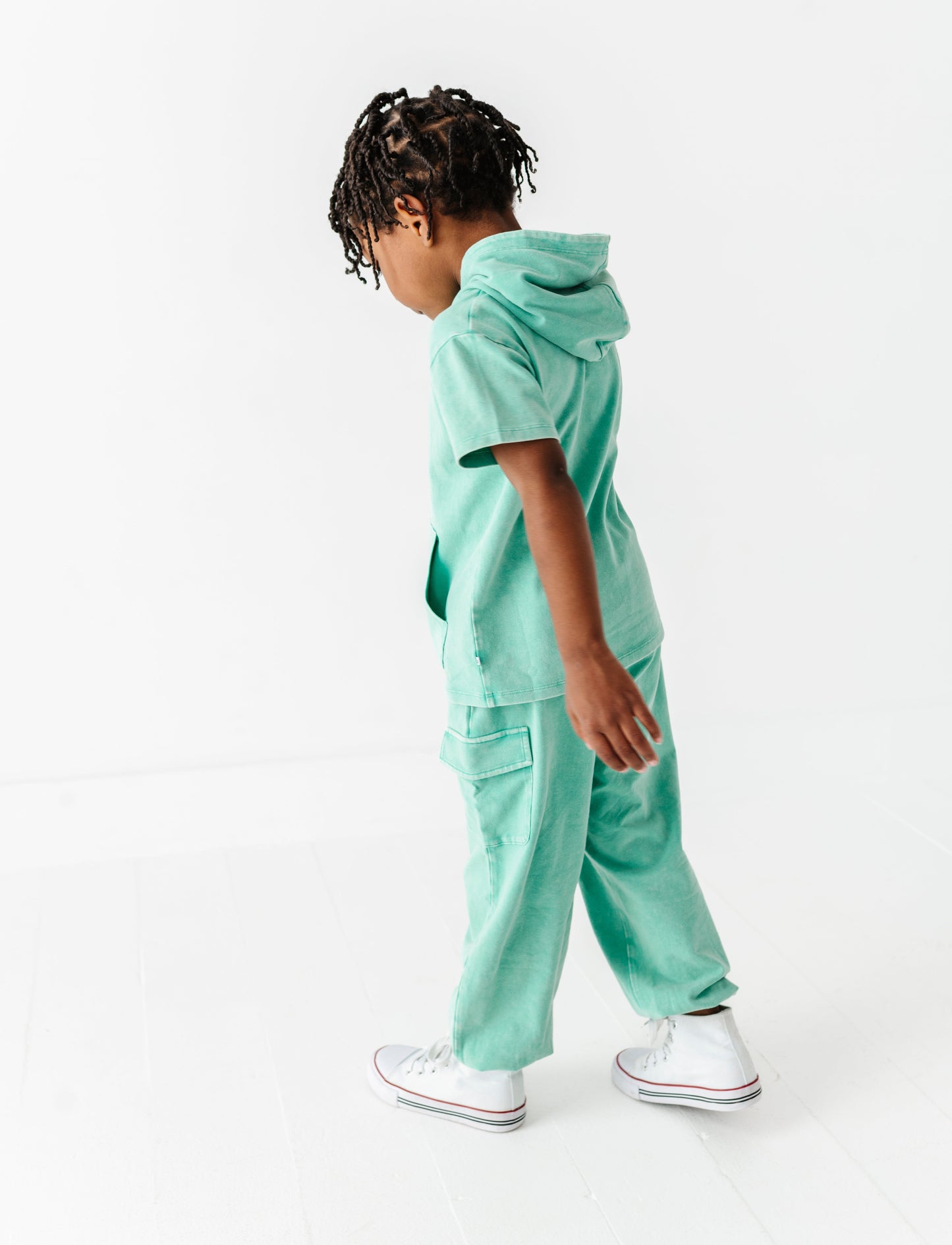 Child wearing a mint green outfit on a white background