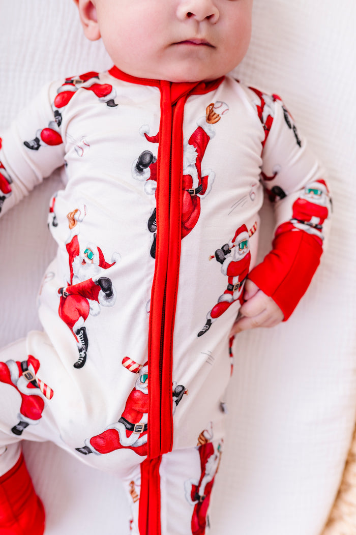 A close-up photo of a baby wearing a Christmas baseball-themed bamboo convertible romper