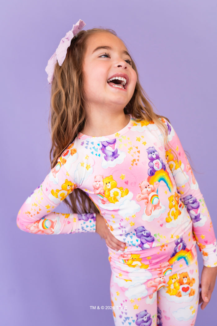 Child wearing a colorful Care Bears™ bamboo pajama set against a purple background