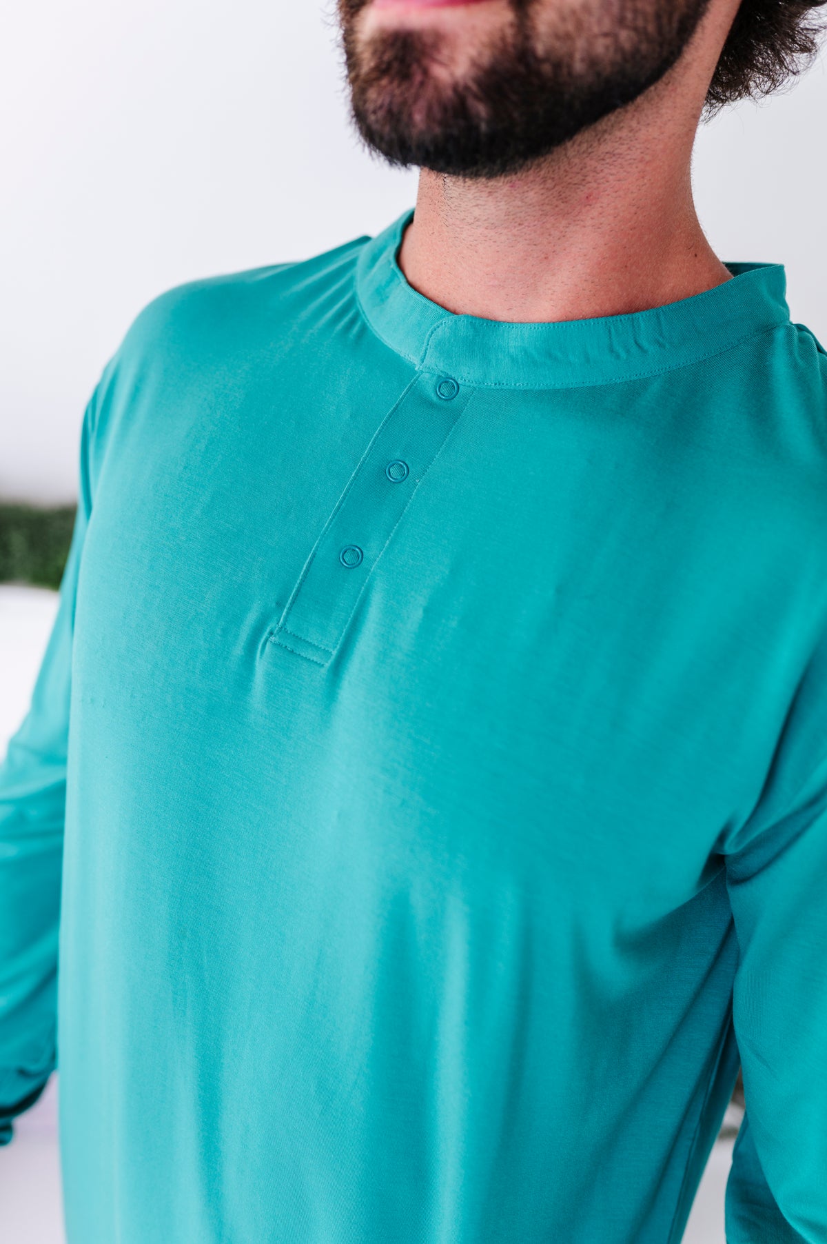 A close-up detail shot of a solid green henley bamboo pajama tee