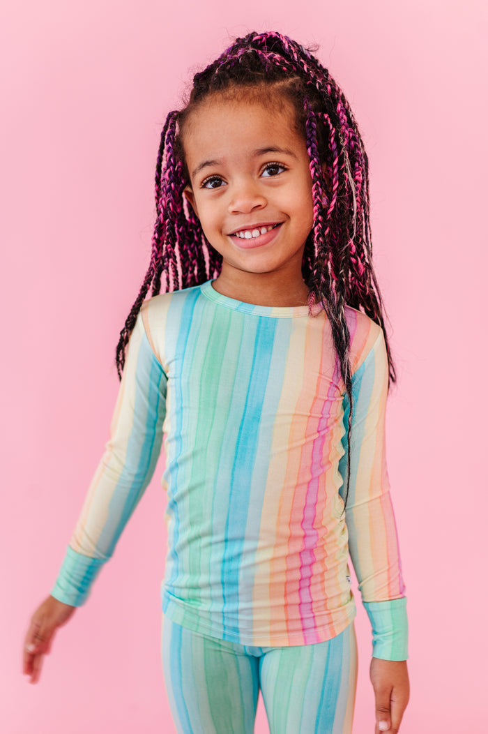 Child wearing a colorful striped two-piece set on a pink background