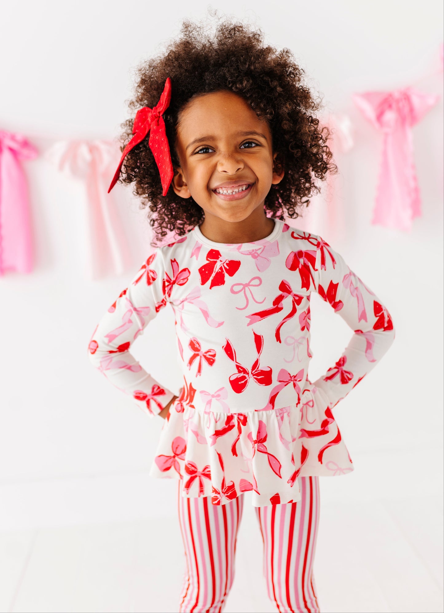 Girl wearing Blushing Bows bamboo cotton peplum top with pink and red bow print