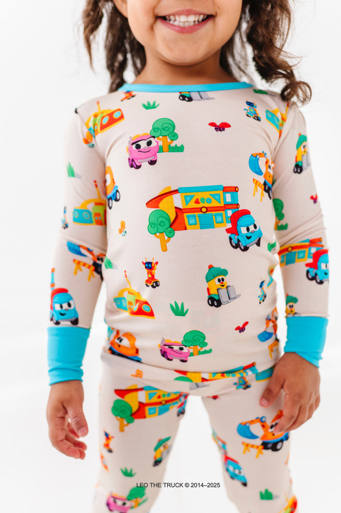 Little girl wearing bamboo Leo the Truck pajamas on a white background