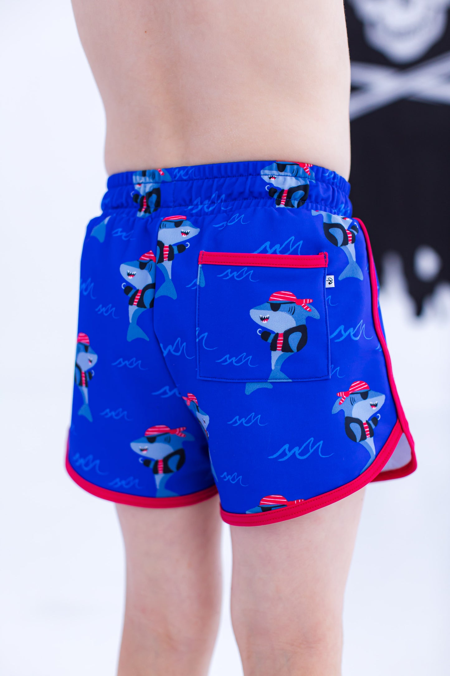 Back view of Sebastian Swim Shorties highlighting functional back pocket, elastic waistband, and shark print