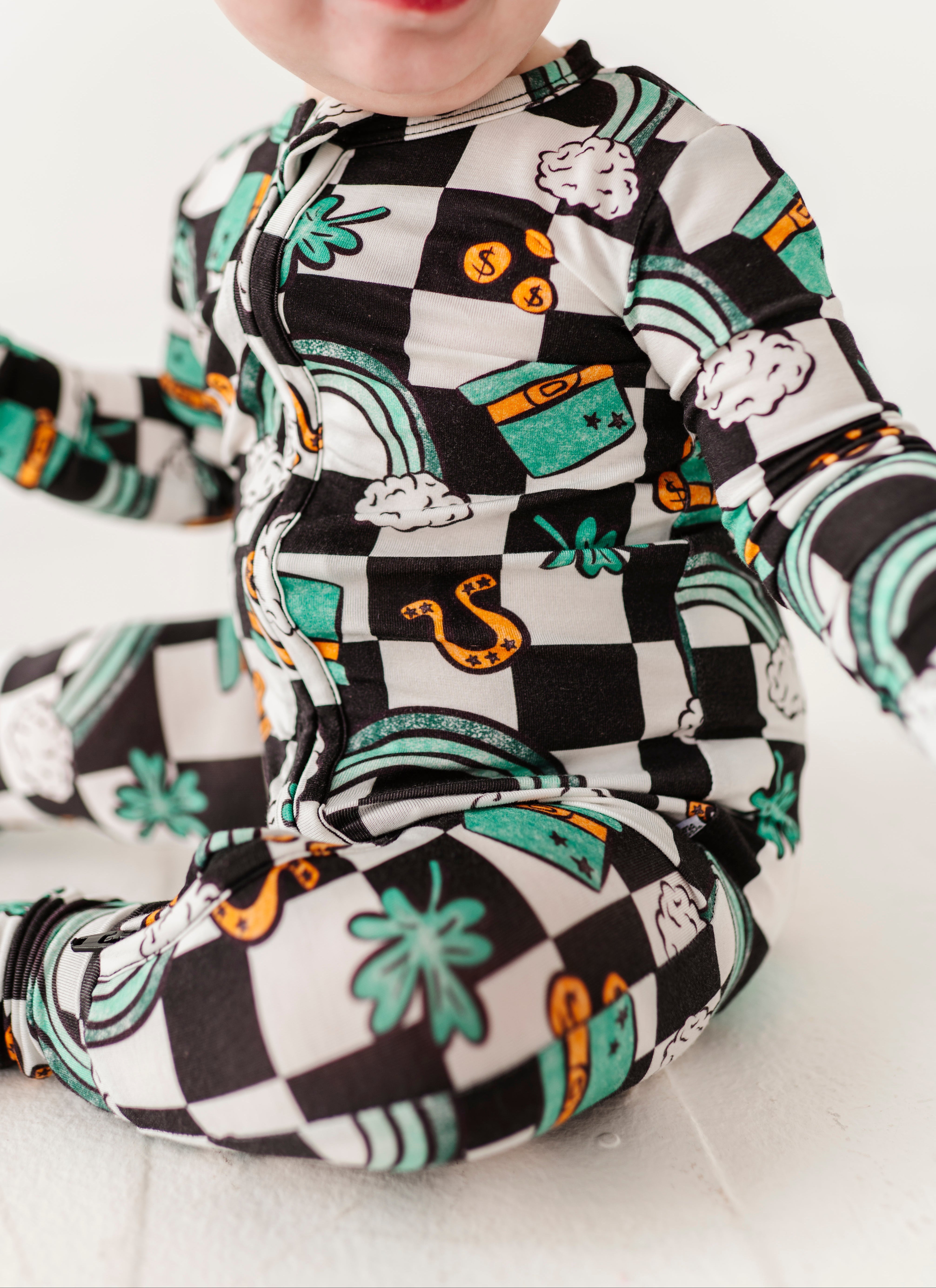 Close-up shot of a bamboo St. Patrick's Day themed convertible romper featuring top hats, four leaf colors, rainbows, and more!