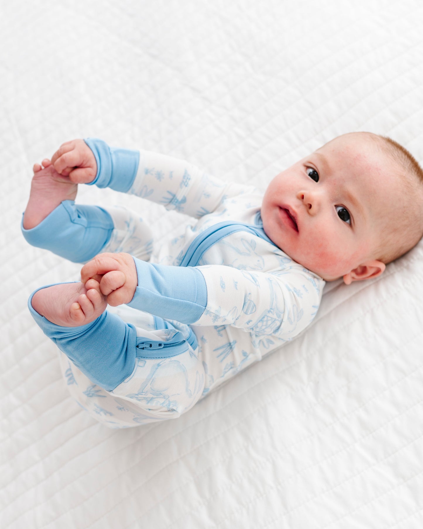 Baby wearing blue and white Easter bamboo romper on a white background