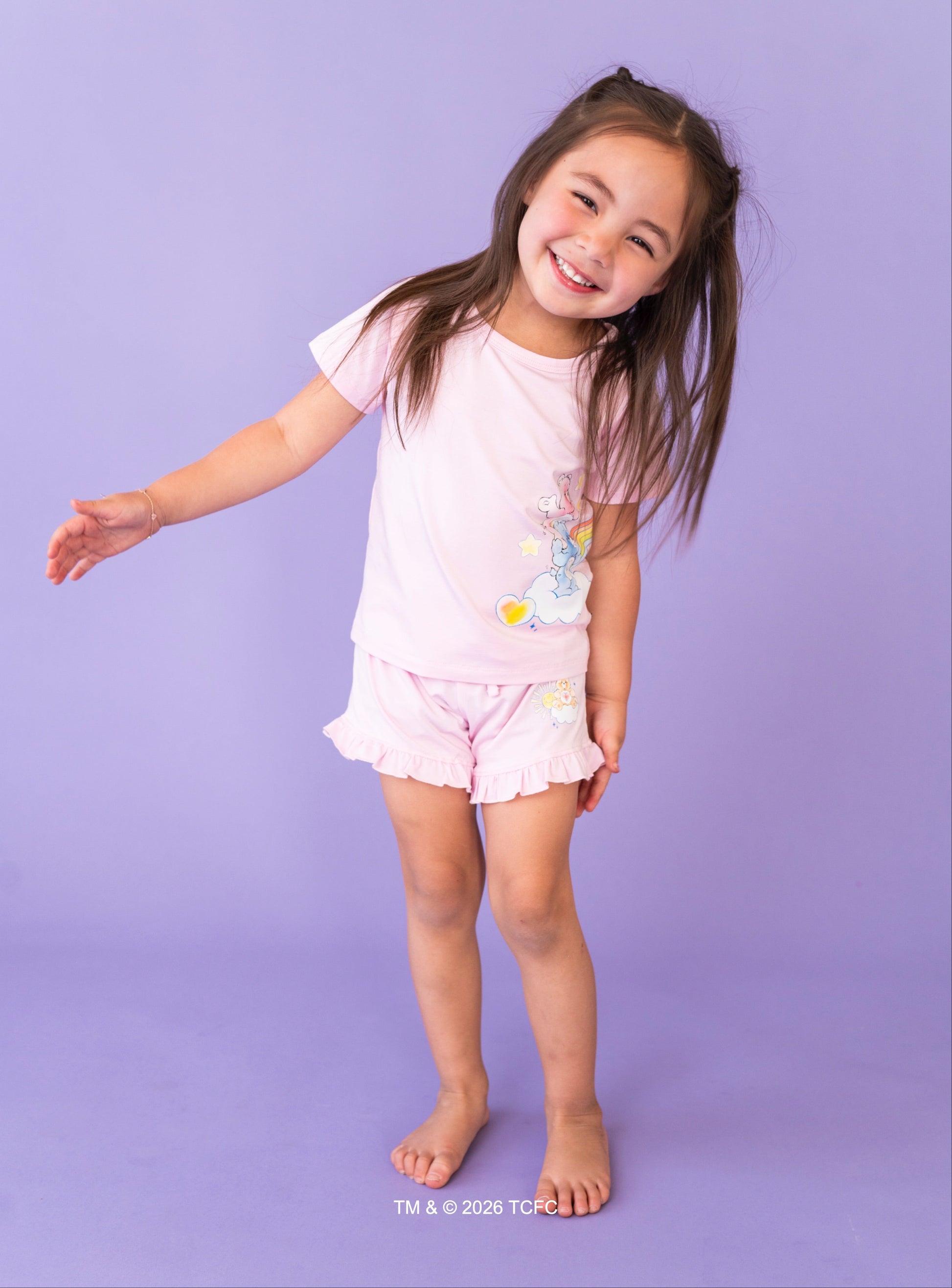 Young girl in a lilac two-piece set with Care Bears™ design on a purple background