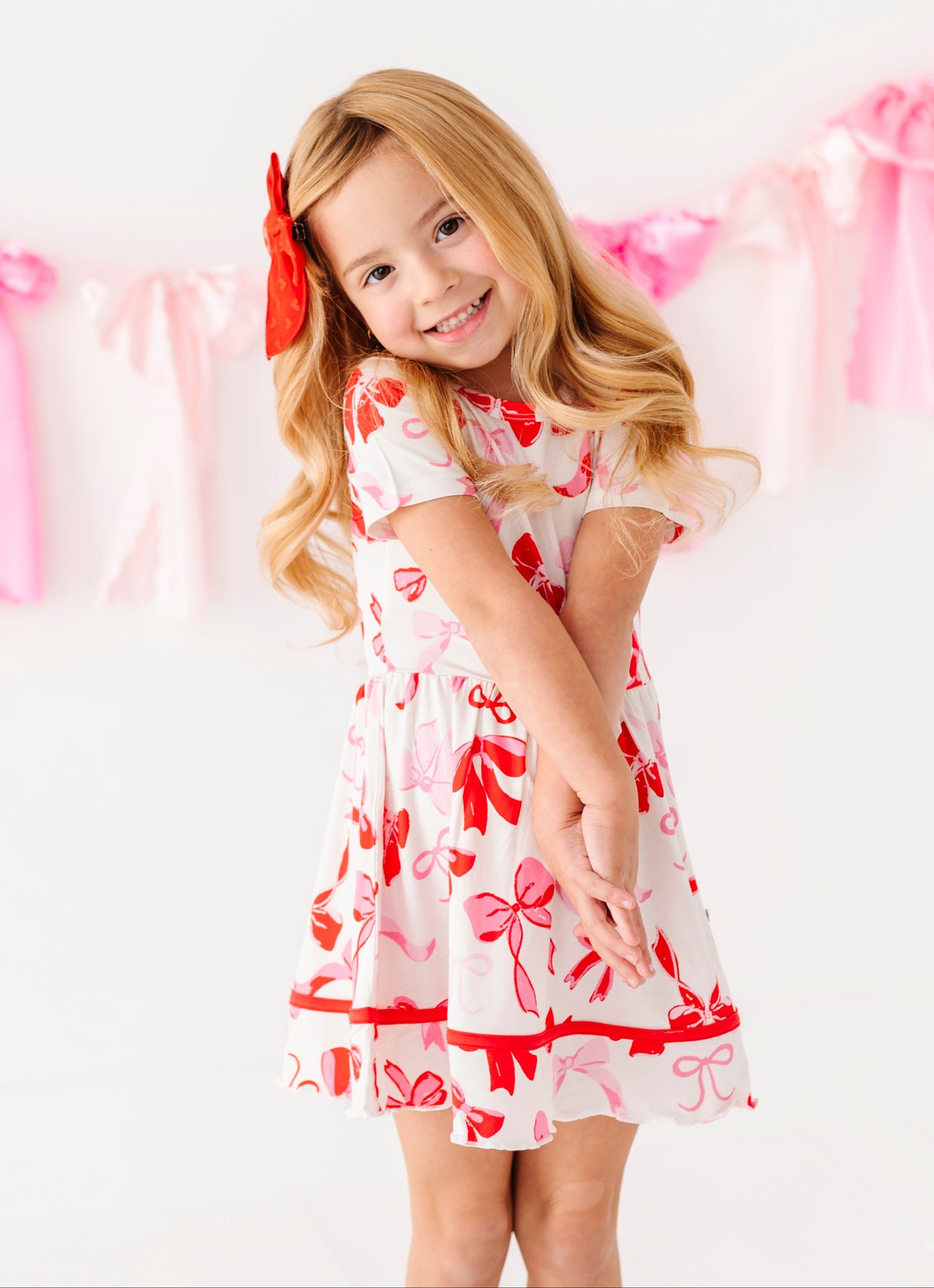 Toddler girl wearing bamboo twirl dress with red and pink bow details