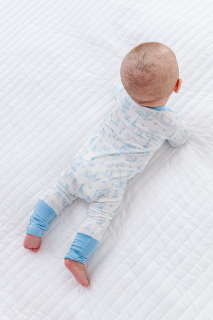 Baby lying on a textured white surface wearing a blue and white bamboo Easter onesie.