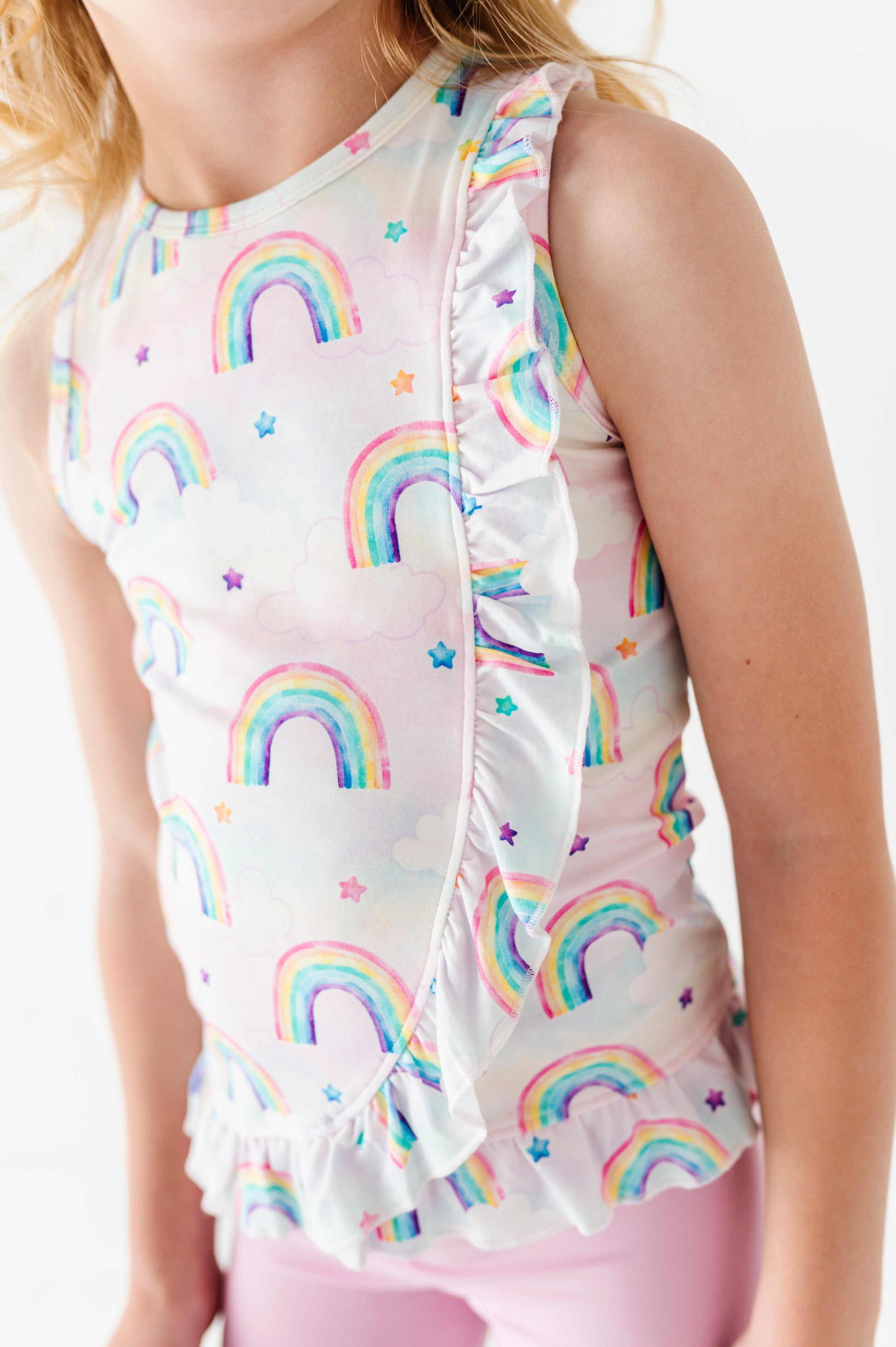 Child wearing a sleeveless bamboo cotton peplum top with rainbow pattern on a white background