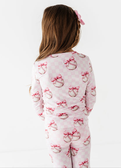 Child wearing a pink bamboo pajama set with bow pattern on a white background