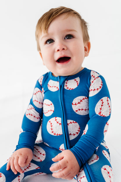 Baby wearing a blue bamboo romper with baseball patterns on a white background