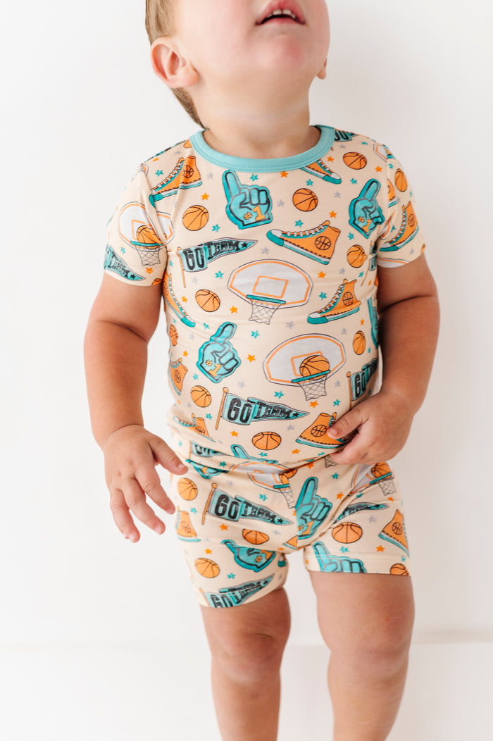 Child wearing a bamboo short set with sports-themed design on a plain background
