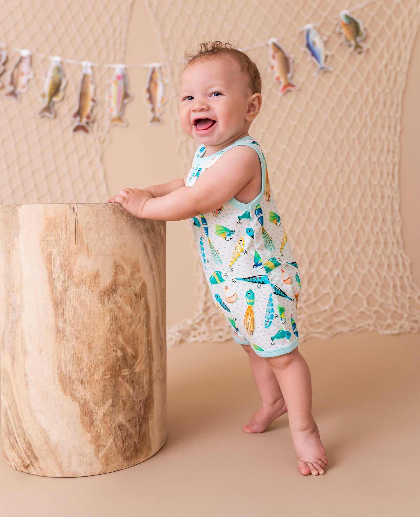 Baby standing next to a wooden block with a fish-themed backdrop
