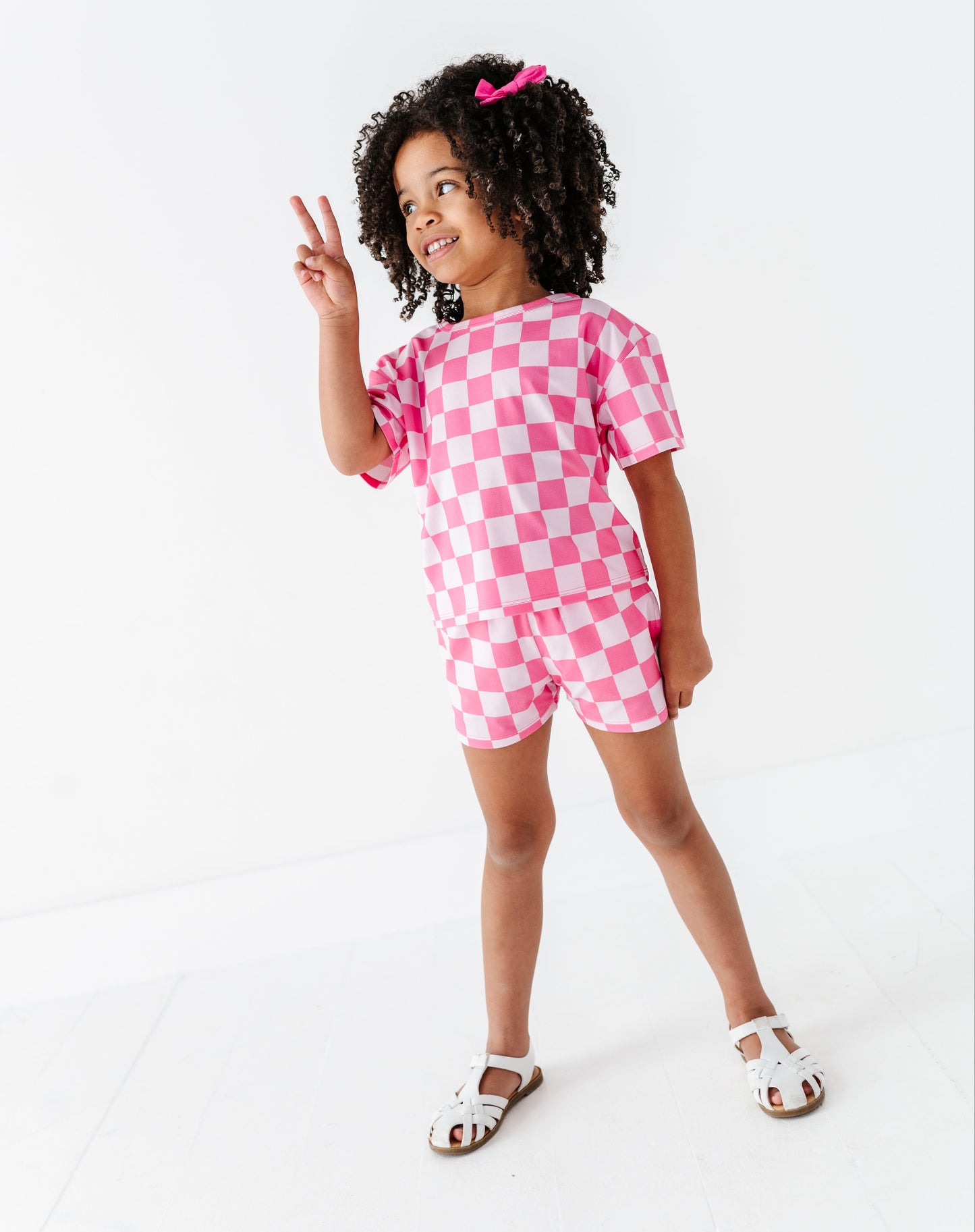 Child wearing a pink checkered outfit on a white background
