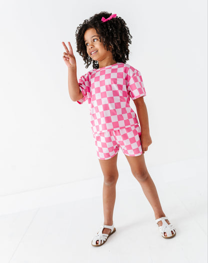 Child wearing a pink checkered outfit on a white background