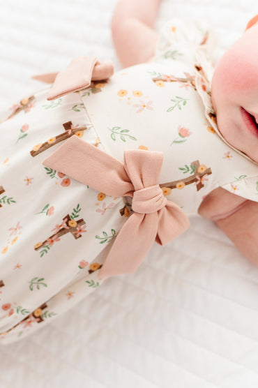 baby girl in a cross with florals bubble romper on a white background 