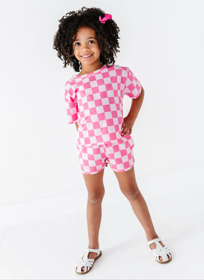 Child wearing a pink and white checkered outfit on a white background