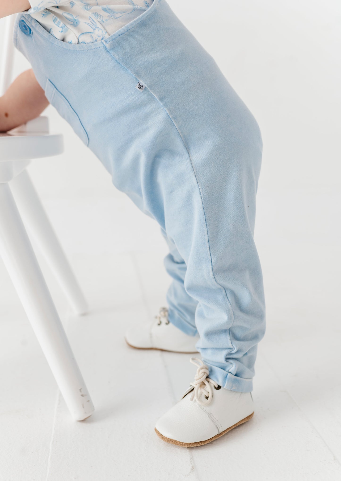 Light blue pants worn by a child standing by a white stool.