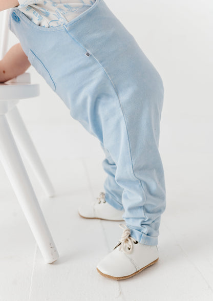 Light blue pants worn by a child standing by a white stool.