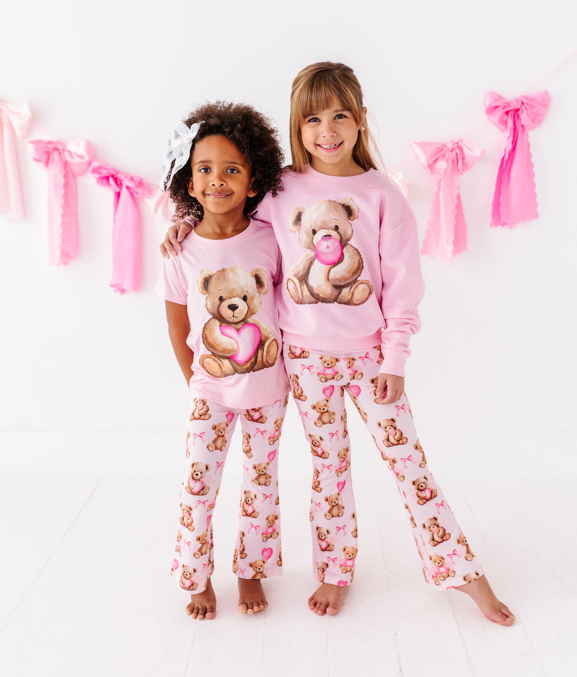 Full body view of child wearing pink teddy bear graphic t-shirt with matching teddy print leggings