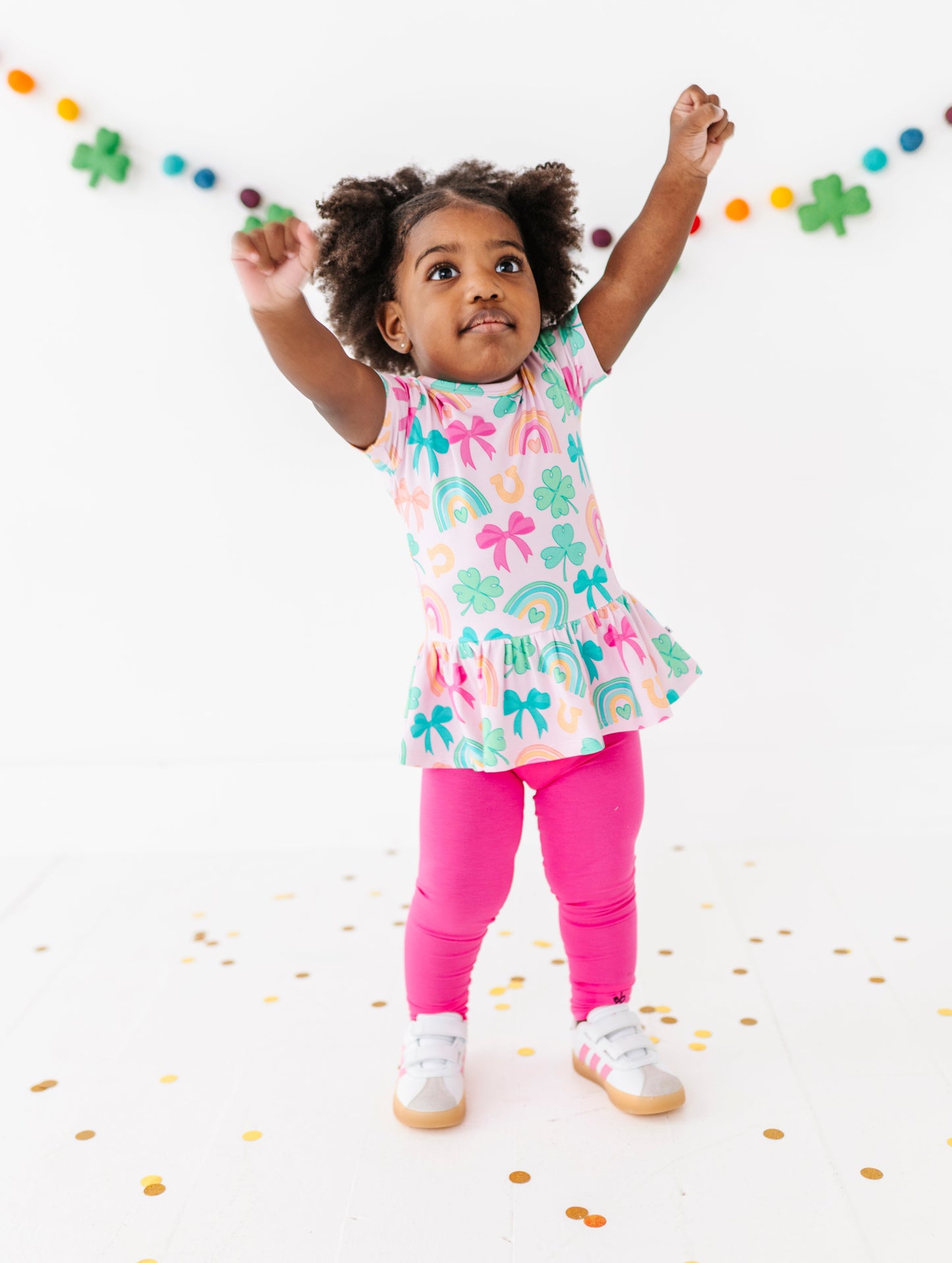 Child wearing a colorful bamboo peplum top with hot pink bamboo leggings on a white background