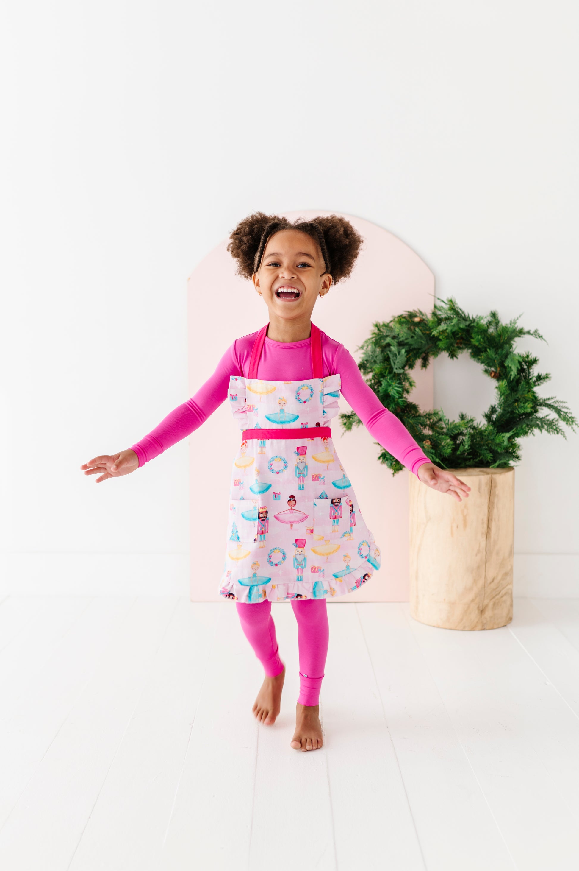 Child wearing Sugarplum ruffle baking apron with Nutcracker holiday print