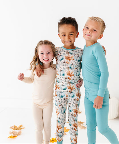 Three children wearing bamboo pajamas standing together on a white background