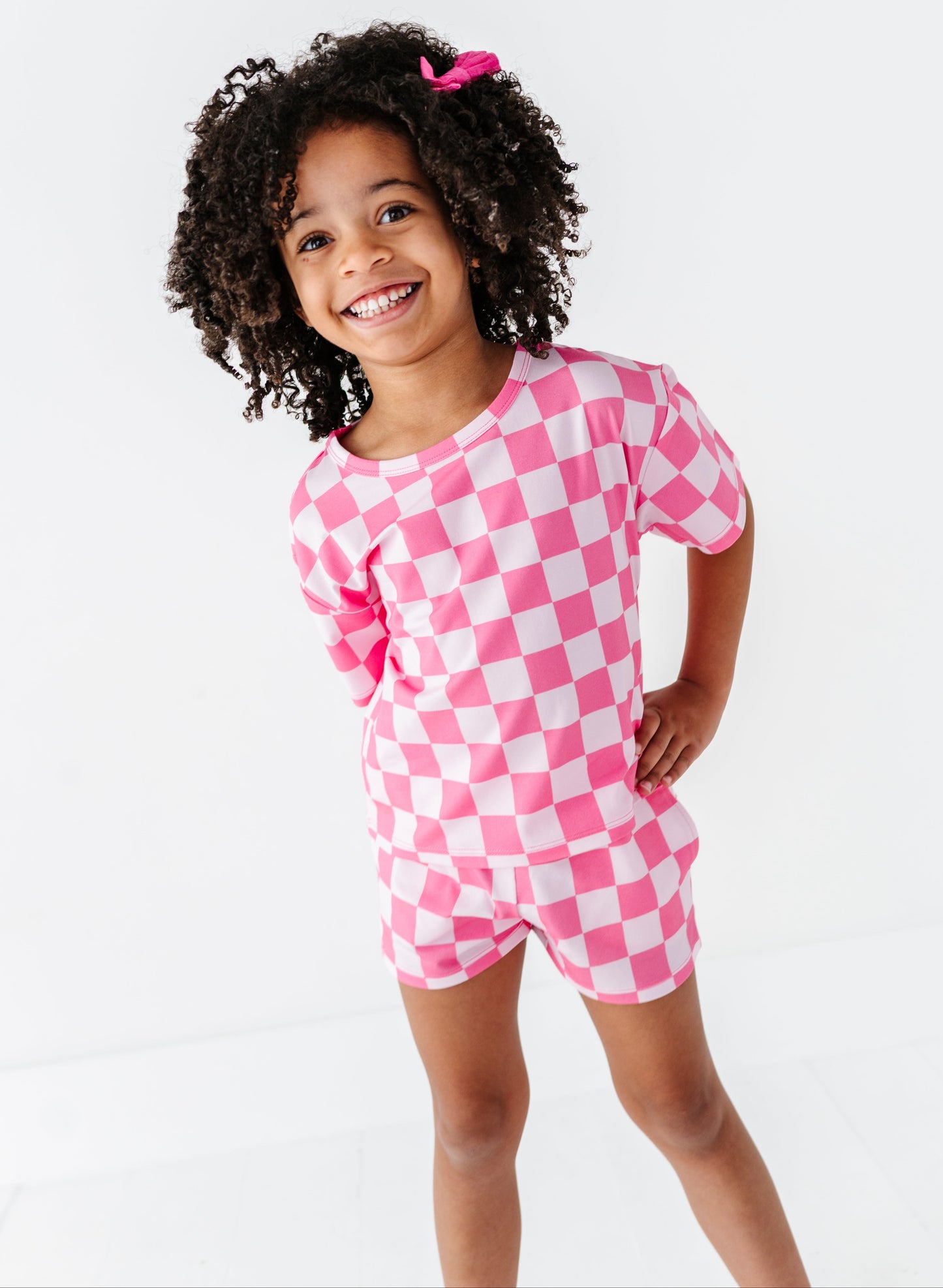 Child wearing a pink and white checkered outfit on a white background